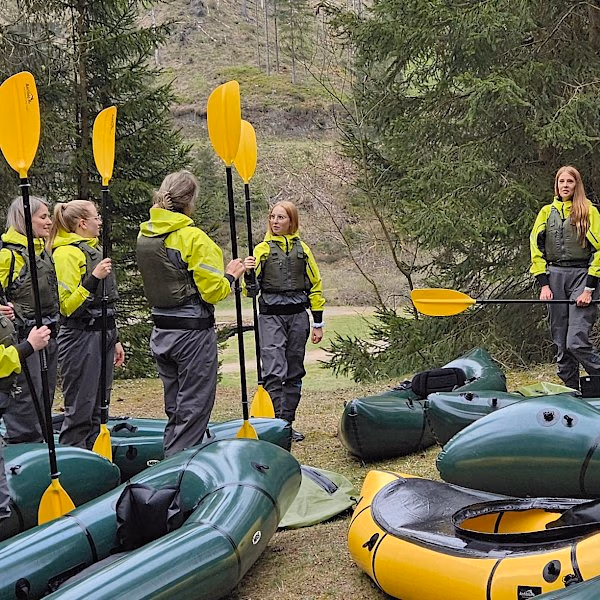 Diese jungen Frauen haben sich am Ufer auf die Paddeltour vorbereitet
