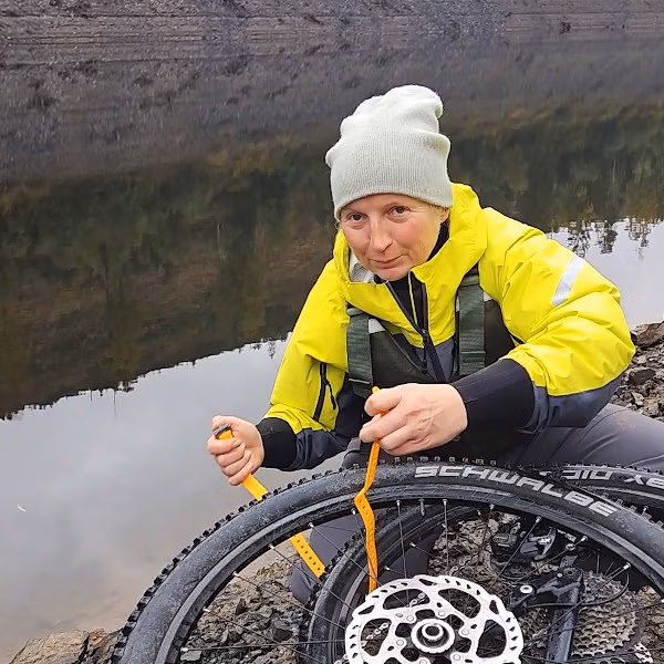 Anne befestigt das Bike mit Gurten auf dem Packraft