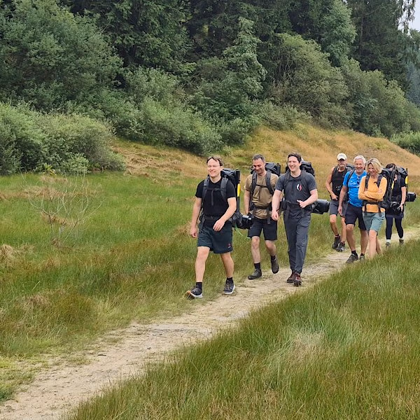 Diese Gruppe wandert mit den Rucksäcken zum Ufer der Okertalsperre