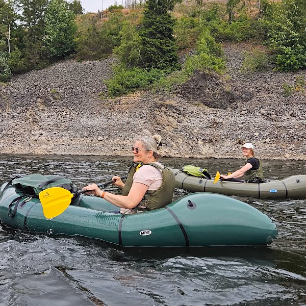 Eine Frau paddelt im Packraft mit ihrer Tochter über den See
